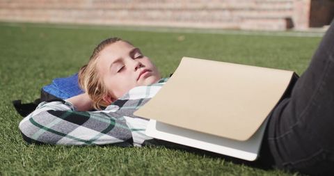 Teen Girl Relaxing on Lawn with School Supplies