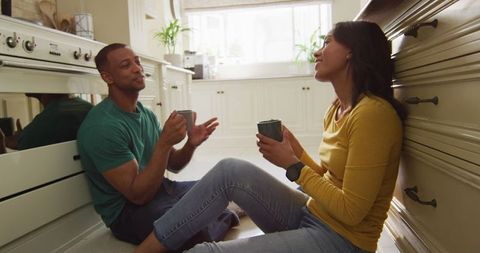 Biracial Couple Enjoying Coffee Together on Kitchen Floor