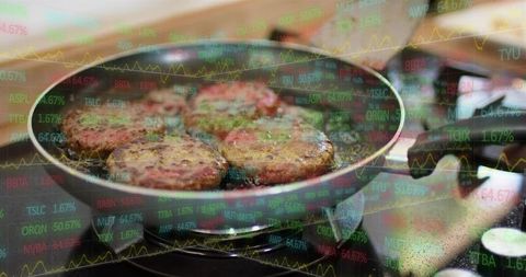 Sizzling burger patties browning in skillet with stock market overlay