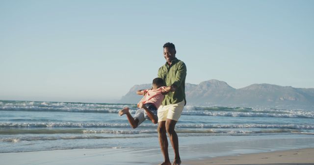 Happy african american father playing with son on sunny beach - Download Free Stock Photos Pikwizard.com