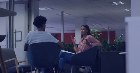 Colleagues discussing in modern lounge, woman gesturing with notes during informal meeting
