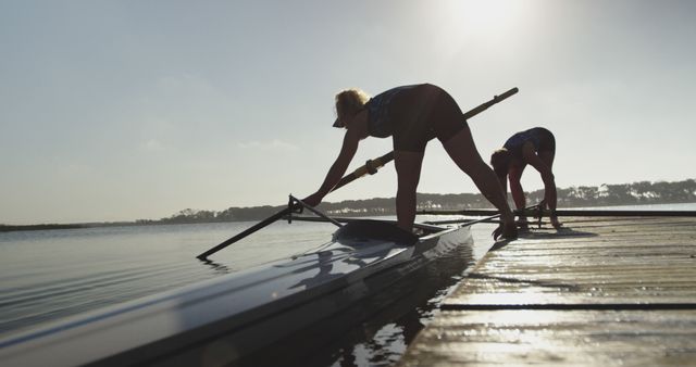 Two young Caucasian women prepare a kayak by the water at sunrise - Download Free Stock Photos Pikwizard.com