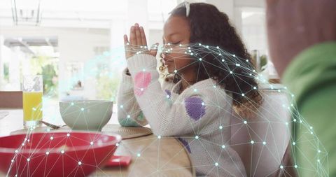 Girl praying at family breakfast with digital mesh overlay and cozy knit sweater