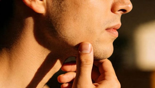 Man touching chin showing stubbled jawline contemplative profile close-up headshot