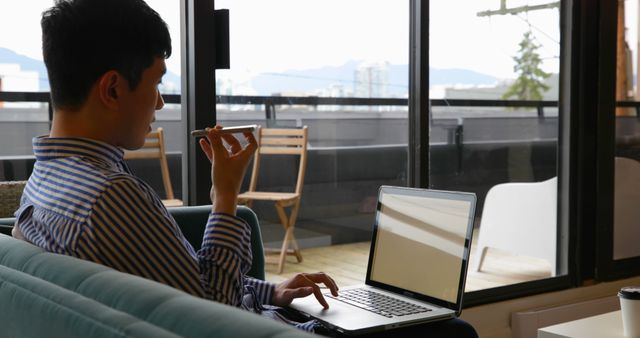 Young Man Talking on Smartphone While Working on Laptop - Download Free Stock Images Pikwizard.com