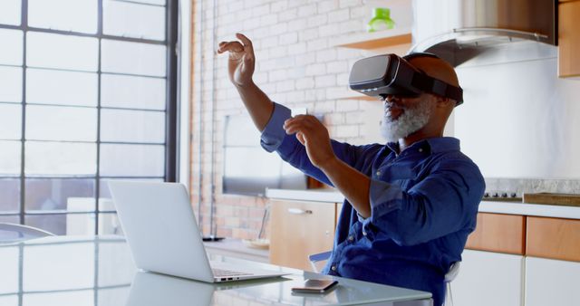 Senior man engaging with virtual reality technology in a modern loft apartment. Ideal for illustrating technology adoption among older generations, digital experience at home, and futuristic living environments. Great for articles, blogs, and advertisements focusing on VR technology, tech-savvy seniors, and innovative home setups.