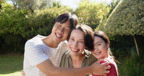 Happy Asian Family Hugging in Sunlit Garden