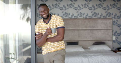 Relaxed Man Holding Mug Beside Bedroom Sliding Glass Door