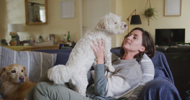 Smiling caucasian woman kissing and cuddling her pet dog sitting on sofa at home. lifestyle, pet, companionship and animal friendship concept.