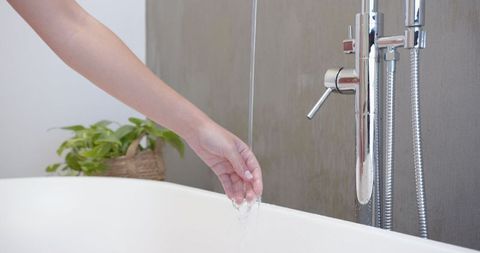 Woman's Hand Testing Water in Minimalist Bathroom