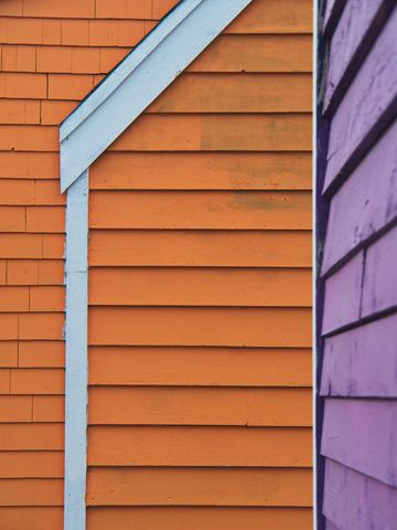 Bright orange clapboard siding with white trim and contrasting purple neighbor wall
