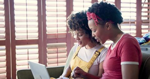 Women Smiling while Online Shopping with Laptop and Credit Card at Home