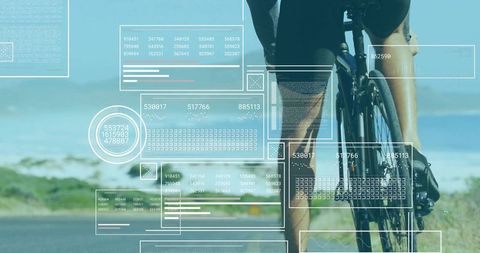 Male cyclist standing pushing road bike on coastal road with futuristic hud overlay