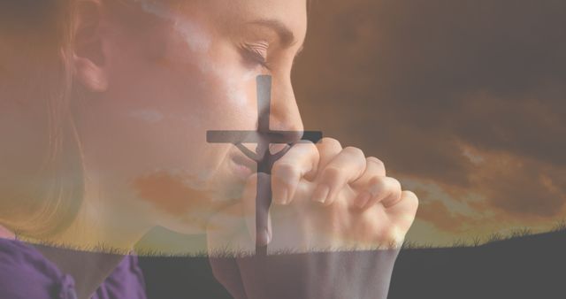 This image features a woman in prayer with hands clasped, superimposed with the silhouette of a cross during a sunset. Ideal for use in religious or spiritual content, faith-based messages, motivational posters, and meditation guides.