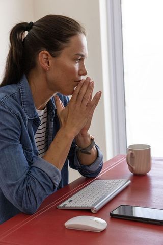 Woman Contemplating at Desk with Keyboard and Smartphone