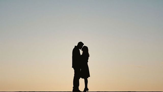 Romantic couple silhouette standing close on horizon at sunset with soft twilight sky
