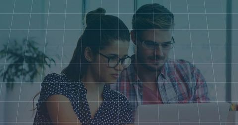 Young professionals collaborating over laptop in modern office with natural light