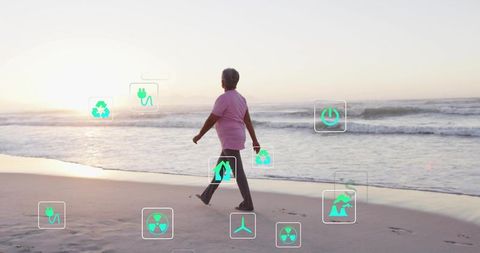Senior walking on beach at sunset with augmented reality sustainability and energy icons