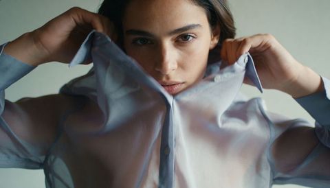 Female model lifting blouse collar in moody editorial close-up, fashion portrait