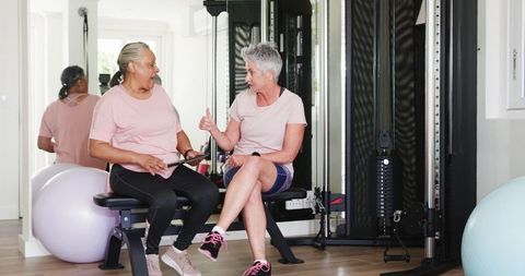 Senior Lesbian Couple Exercising in Home Gym Using Tablet