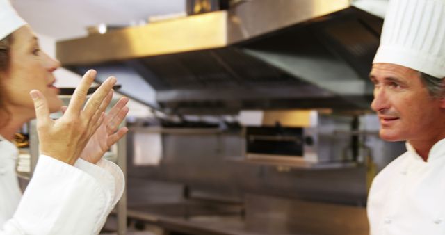 Chefs in a professional kitchen casually discussing preparations. Chefs dressed in traditional white uniforms and chef hats. This image is useful for illustrating collaboration, teamwork, and the professional environment in culinary establishments. Great for websites, blog posts, and articles about cooking, restaurant management, and team dynamics in the culinary field.