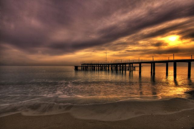 Sunset Over Serene Beach with Pier and Dramatic Sky - Download Free Stock Images Pikwizard.com