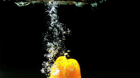 Yellow Pepper Sinking in Water with Bubbles Creating Unique Splash