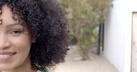Confident Woman Smiling Outdoors with Modern Architecture Background