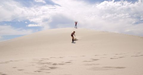 Caucasian Couple Sandboarding on Vast Desert Dunes under Clear Sky - Download Free Stock Images Pikwizard.com