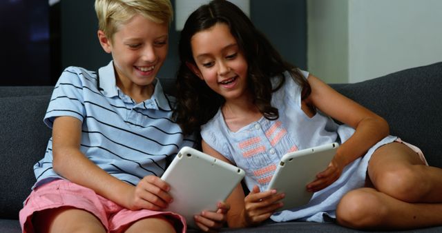 Smiling Kids Sitting on Sofa Using Digital Tablets - Download Free Stock Images Pikwizard.com