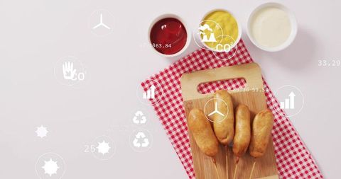 Corn dogs flatlay featuring eco infographic overlay on gingham cloth and wooden board