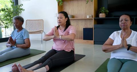 Senior african american women practicing seated meditation on yoga mats in wellness studio