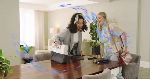 Meeting friends at dining table: two women greeting, unpacking bags, casual home workspace