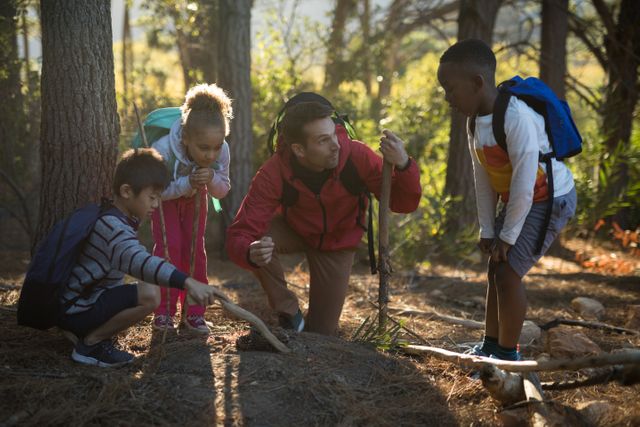 Teacher guiding children on a nature exploration in a forest, examining soil and plants. Ideal for educational materials, environmental awareness campaigns, outdoor adventure promotions, and school field trip brochures.