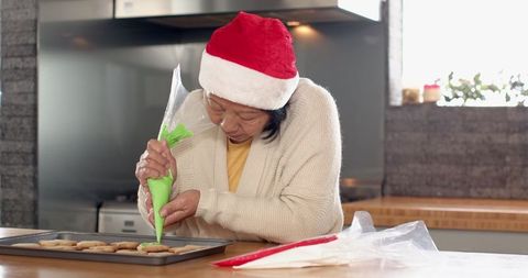 Senior Woman Decorates Holiday Cookies with Green Icing