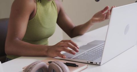 African american woman typing and gesturing at laptop in minimalist modern home workspace