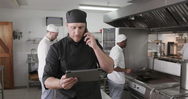 Restaurant Chef Talking on Phone While Using Tablet in Professional Kitchen - Download Free Stock Images Pikwizard.com