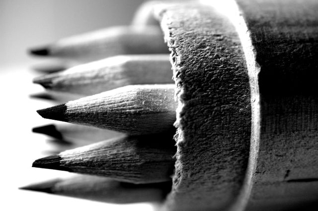 Looking closely at a bunch of wooden pencils inside a cylindrical container. Pencils are sharply pointed. Ideal for educational covers, stationary promotions, art supply ads, or black and white themed designs.