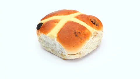 Single Hot Cross Bun with Raisins on White Background