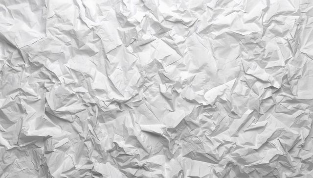 Crumpled white paper texture showing deep creases, soft shadows and minimalist surface