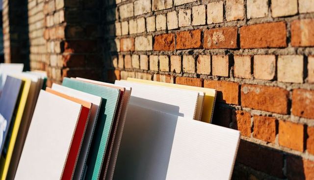 Sunlit canvases leaning on weathered brick wall casting long shadows with colorful edges