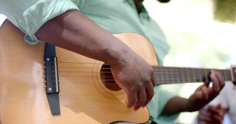 Close-Up of Hands Playing Acoustic Guitar at Outdoor Gathering