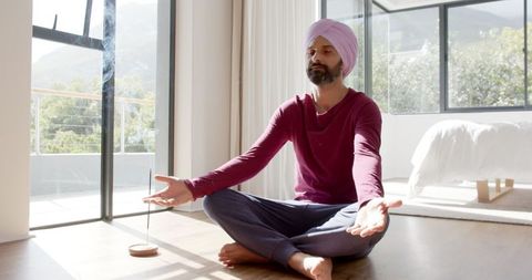 Man in turban meditating with incense in sunlit room