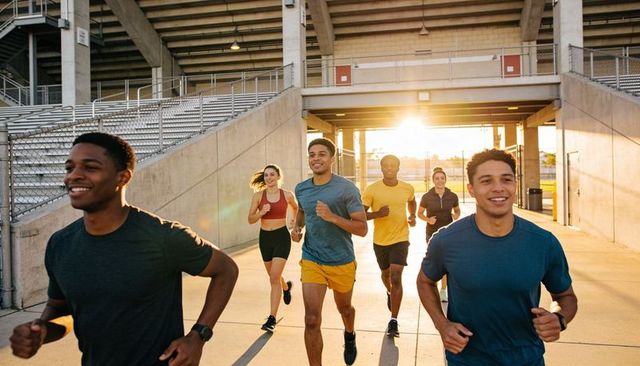 Sunlit group running on stadium concourse during golden hour outdoor fitness training team
