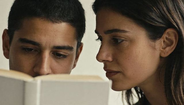 Couple leaning close reading hardcover book together in cozy living room moment of intimacy