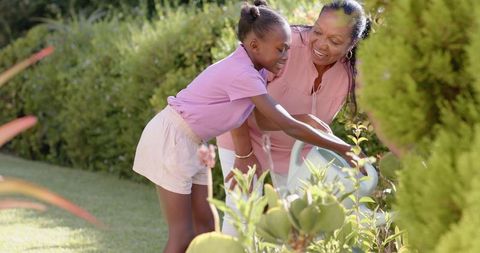 Grandmother and Granddaughter Bonding While Watering Garden