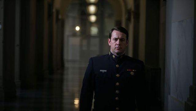 Uniformed Officer Walking Across Illuminated Marble Corridor