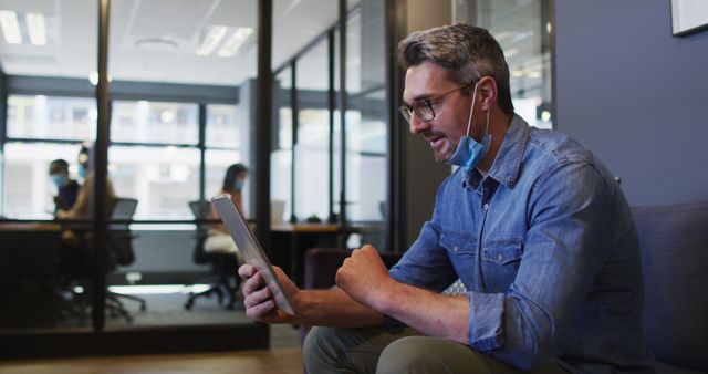 Professional wearing mask and headphones using tablet in modern office - Download Free Stock Images Pikwizard.com