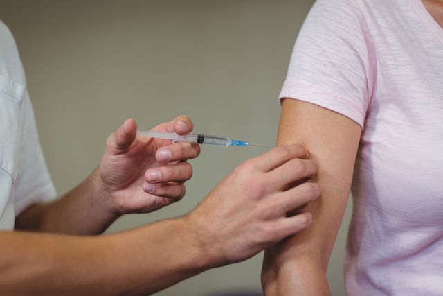 A healthcare professional is administering an injection to a patient's arm. Ideal for use in medical, healthcare, and vaccination-focused content, as well as illustrating doctor-patient interactions and immunization processes.