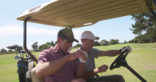 Two male golfers sitting in golf cart, checking scorecard amid lush greenery. Ideal for use in sports articles, advertisements for golf equipment, brochures for golf resorts, or promotional materials for outdoor activities. Captures casual golf game, teamwork, and recreation.